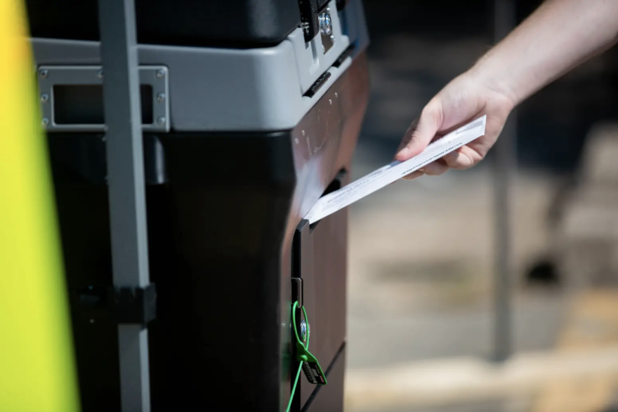 A voter drops off a ballot at the Travis County Tax Office, the only site where mail-in ballots can be hand delivered in the county.