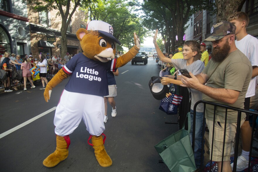 Dugout, the Little League World Series mascot, high-fives a fan during the parade.