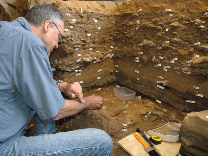 <p>Archaeologist Christopher Henshilwood excavates at the 100,000-year-old levels of the Blombos cave in South Africa.</p>