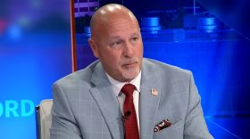 A man sitting at a desk on a news show.