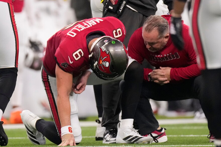 A Buccaneers trainer attends to quarterback Baker Mayfield  