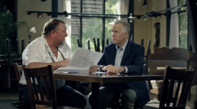 Thom Tillis (right) talks with restaurant owner Jeff Lancaster in a new TV commercial