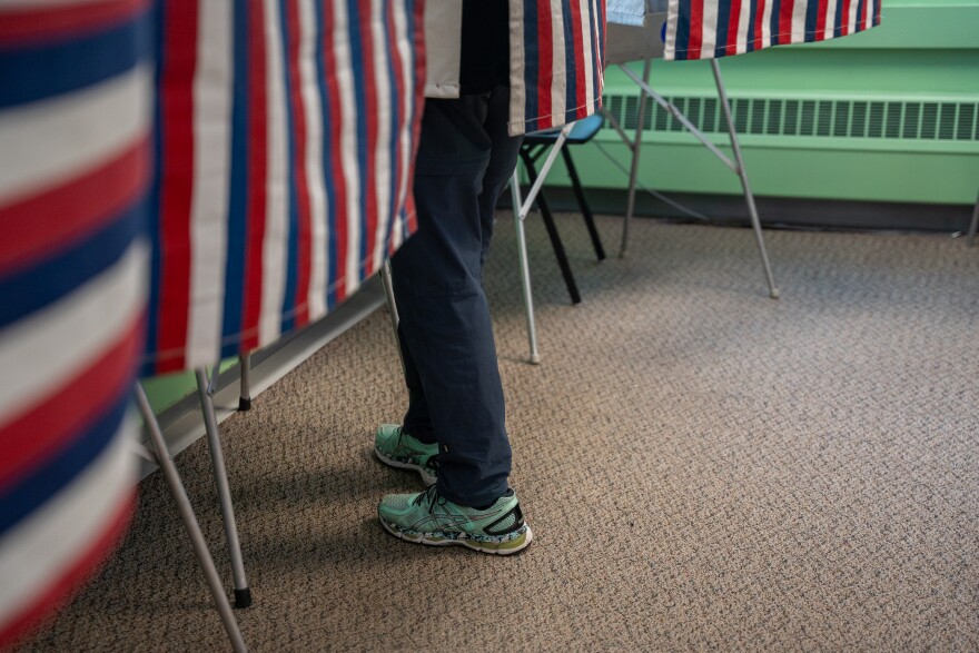 A person's leg sticking out of a voting booth.