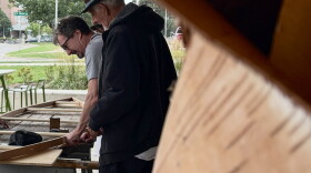Ron J. Paquin framed by birch looking over the canoe build