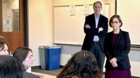  U.S. Senator Ron Wyden and Representative Suzanne Bonamici stand in front of a classroom. Several college students are seen from behind. 