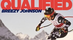 A woman in tight racing gear zooms down a snowy slope on skis with big mountains in the background. Text on the top of the image reads “Qualified, Breezy Johnson.”