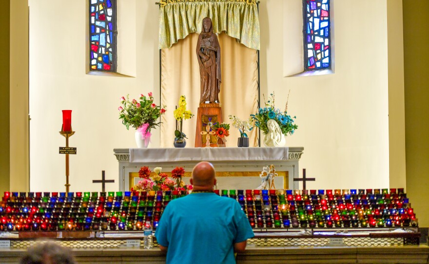 Harold Thomas kneels before the statue of St. Ann.