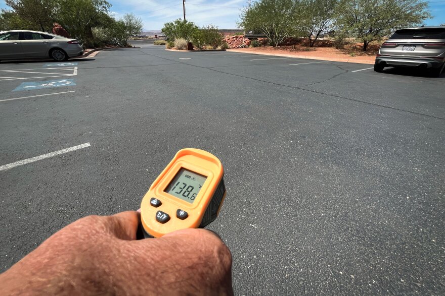 Doug Bennett uses an infrared thermometer to measure the heat of an asphalt parking lot at the Red Hills Desert Garden, Aug. 20, 2026. A nearby sidewalk under a shade tree registered around 45 degrees cooler.
