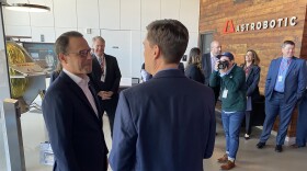 Two men in suits talk to each other, with one of their backs turned.
