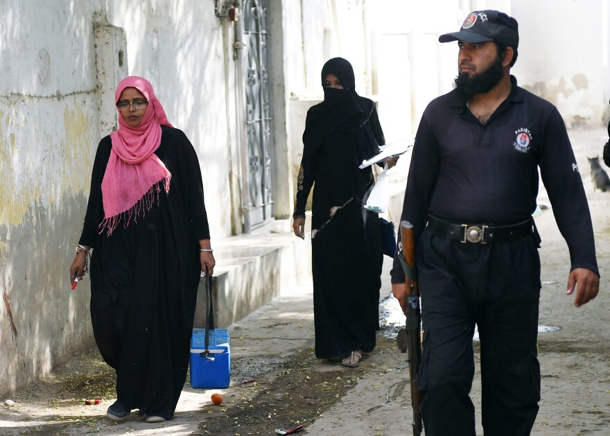 A Pakistani policeman guards a team of polio vaccinators during an immunization drive in Karachi on January 22. Officials have stepped up protection in the wake of the January 18 attack.