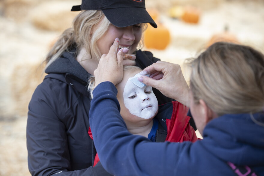 Bennett McGrath paints a kids face at her makeshift pumpkin patch in Petersburg 