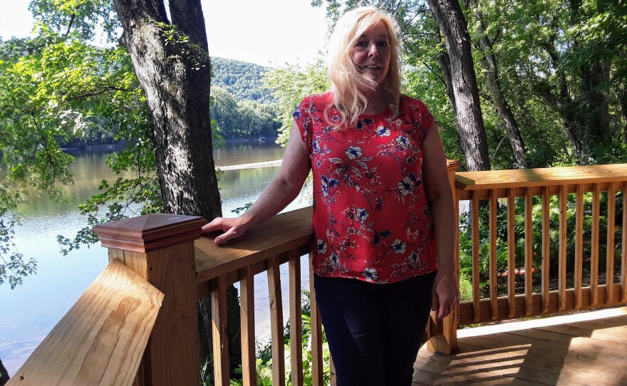 Sherry Patch, town administrator in Sunderland, Massachusetts, stands on a deck that looks out over the Connecticut River. It's part of a new trail in the town. 