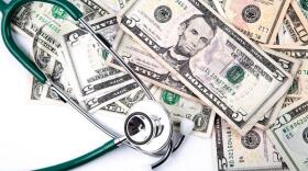 A stethoscope resting on a pile of money.