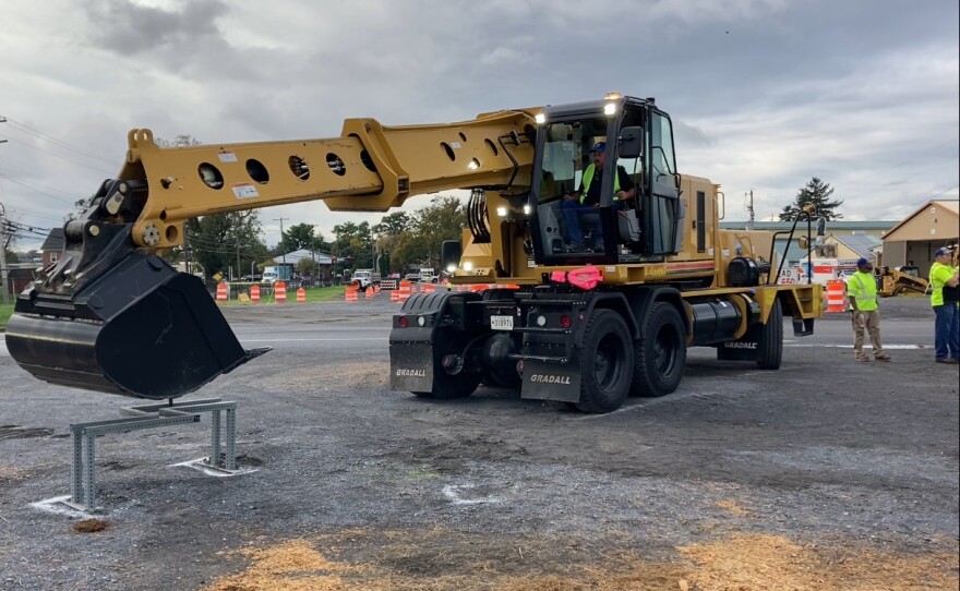 A driver in a Grade All attempting to traversing a metal pole through puzzle without moving it.