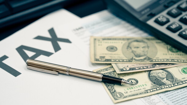 Tax season concept. Tax planning and consulting service business. Pen, calculator, dollar banknote, and income tax return form for filling and calculating tax payments. Money and financial concept.