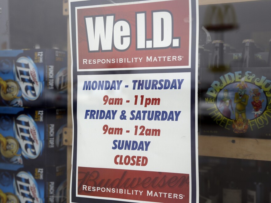A sign on a window at an Elite Beverages liquor store in Indianapolis lists the store's hours.