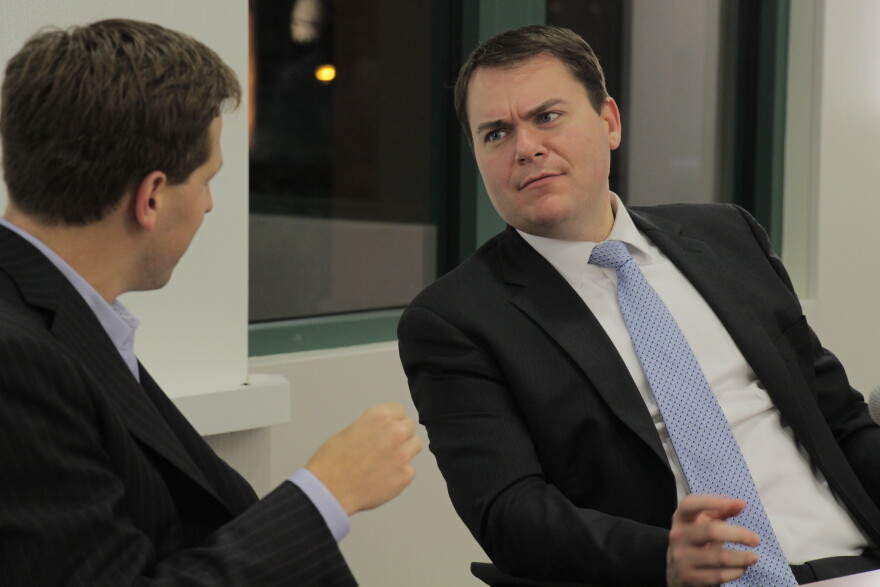 Two white men in suits face each other seated, with the man at left facing away from camera. At right Carl DeMaio frowns at the other man, leaning back. 