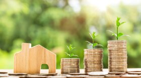 small wood house with stacks of coins