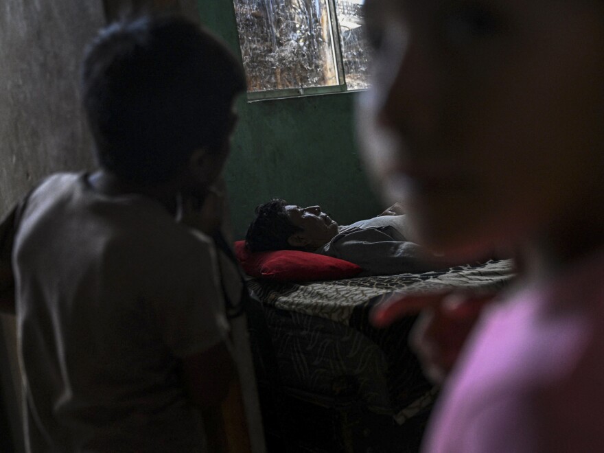 Santos Mendoza (66), who suffers from dengue fever, rests on his bed at his house in the "Refugio San Pablo," a camp of straw houses and tents.