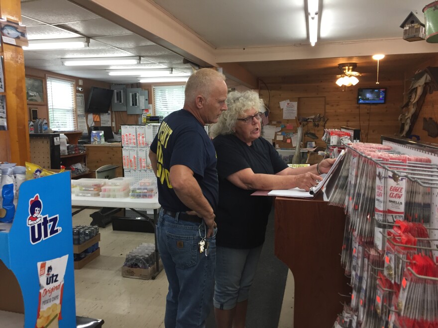 Deerfield Township Trustee Mark Bann (left) and Leslie Steele, who runs Les's Bait, look over a chart of water levels for Berlin Lake.