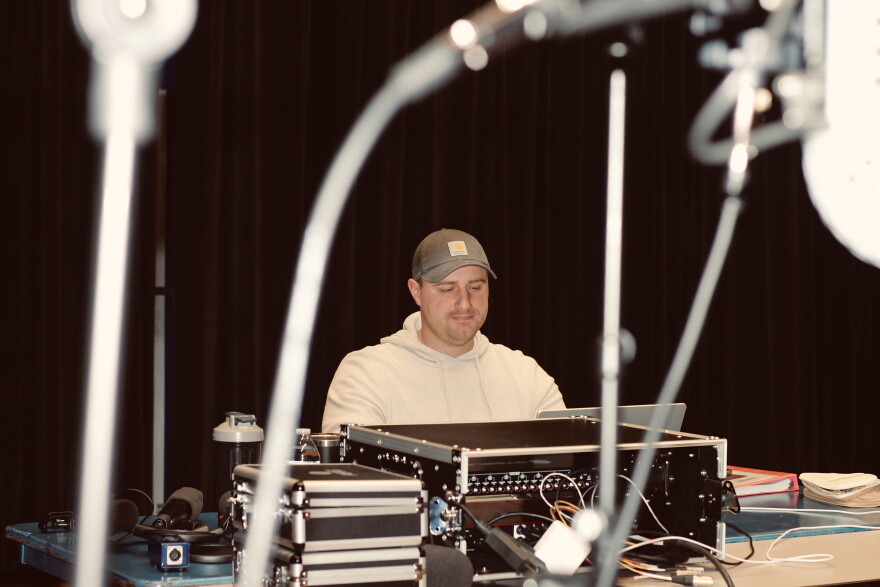 A man sits at a table in front of a laptop.