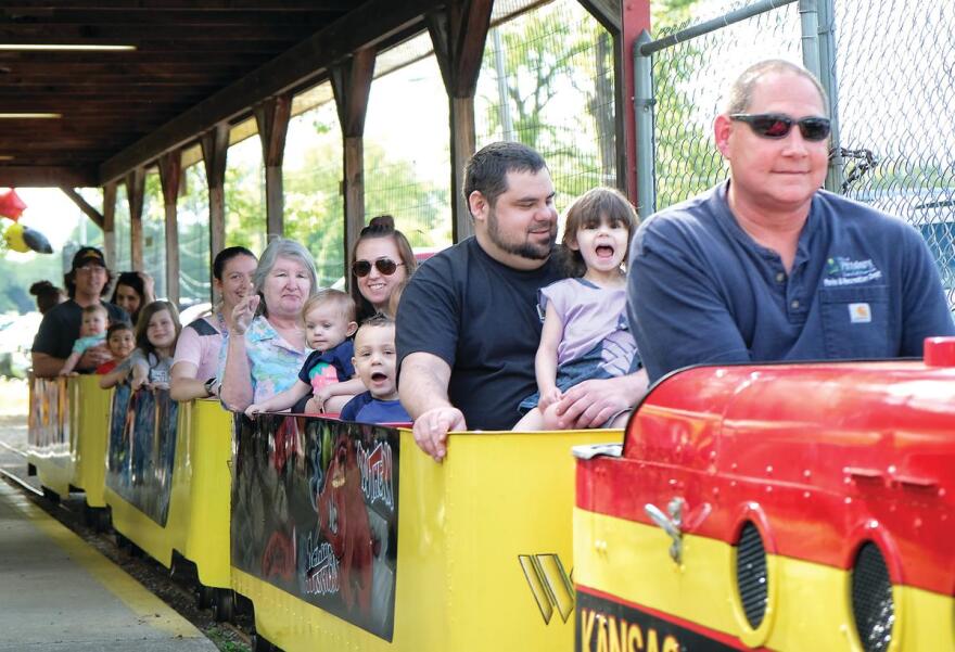  Children and adults ride on a yellow and red mini-train. 