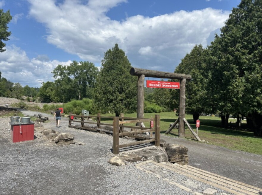 A bright red sign hangs from a wooden frame at the entrance of the Herkimer Diamond Mine. 