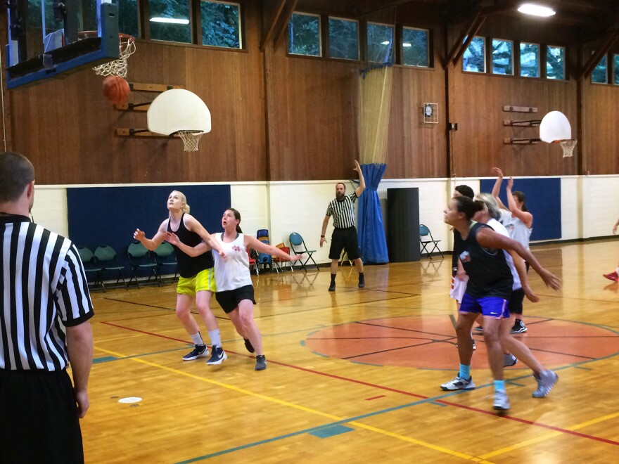 Lei Hart, in black jersey and blue shorts, boxes out an opponent on a free throw attempt. Hart, 41, plays every Monday night at the Hillside Community Center in Portland, Ore.