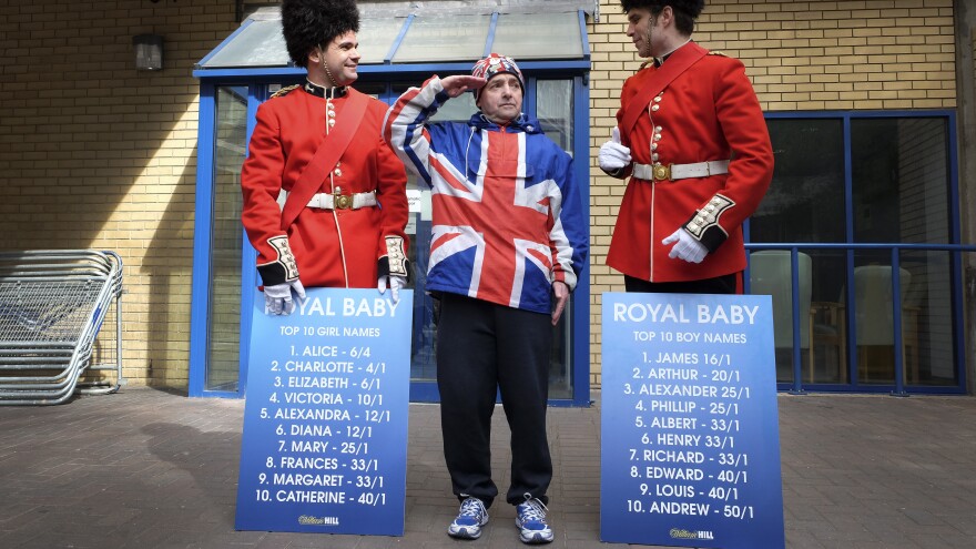 Royal supporter John Loughrey salutes as men dressed as soldiers carry boards with proposed baby names Friday outside the Lindo Wing of St. Mary's Hospital in London.