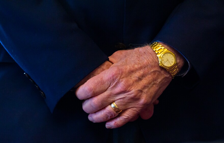 A photo of hands, which show wrinkles, a gold watch and a gold wedding band. 