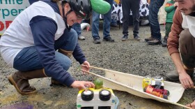 two people put toy cars on a stretcher