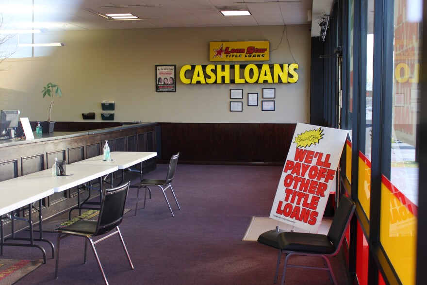 Big yellow letters mounted to the wall inside this LoanStar Title Loans storefront say "cash loans" and a sign propped against the doorway reads, in bright red letters, "We'll pay off other title loans."