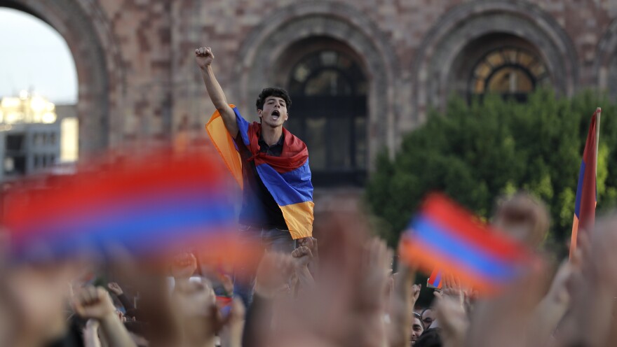 A demonstrator drapes himself in the Armenian flag at a rally supporting Nikol Pashinyan on Wednesday. He was just one of tens of thousands who packed Republic Square in the capital, Yerevan, and blocked roads and interrupted railway service.