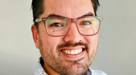 Man with glasses and hawaiian style shirt smiles 