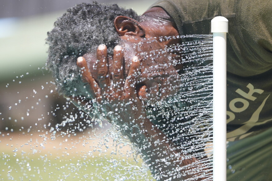 Paul Williams cools off in water while taking a break from yard work in Richardson.