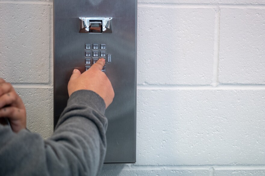 A woman incarcerated at the South Idaho Correctional Institution outside of Boise makes a call from stationary phones that line a wall.
