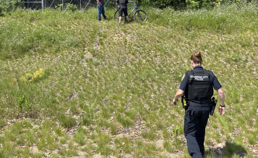 A Lear Corporation employee leads Traverse City police officers to the back of the property, where they believe people have been illegally camping.