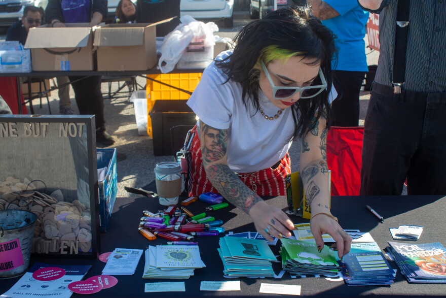 A Shred the Stigma employee arranges harm reduction supplies on a table outside the Oklahoma City Homeless Alliance Day Shelter on Thursday, Oct. 22. The nonprofit was one of several healthcare organizations at a free health and wellness fair for people experiencing homelessness. 