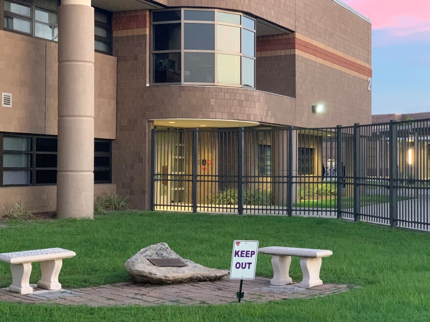 Booker High school exterior, with a pair of benches outside a black fence, and sign that says "Keep Out."