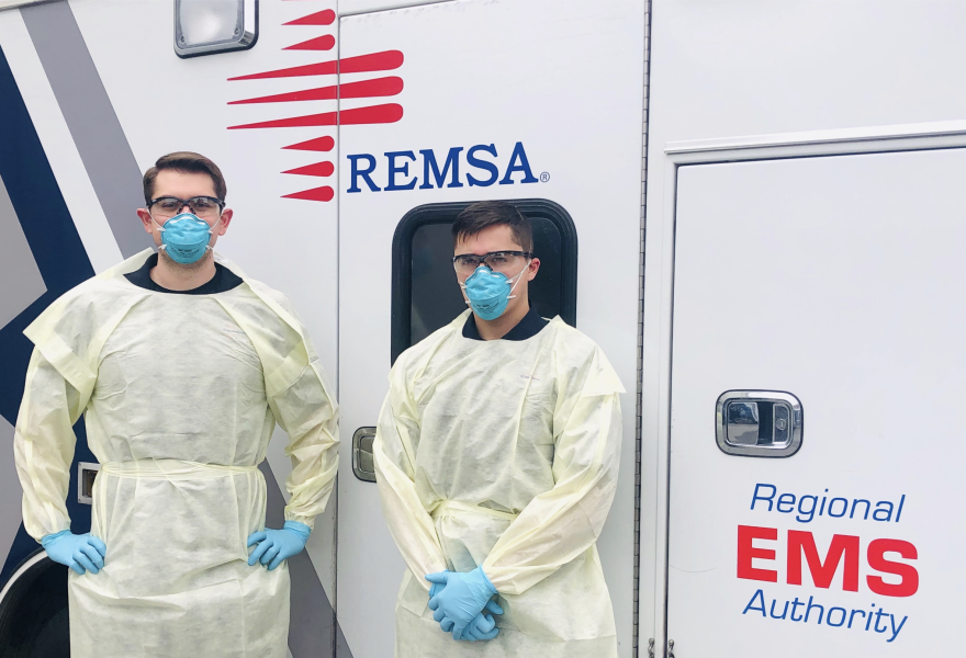 Two first responders standing in front of a REMSA ambulance.