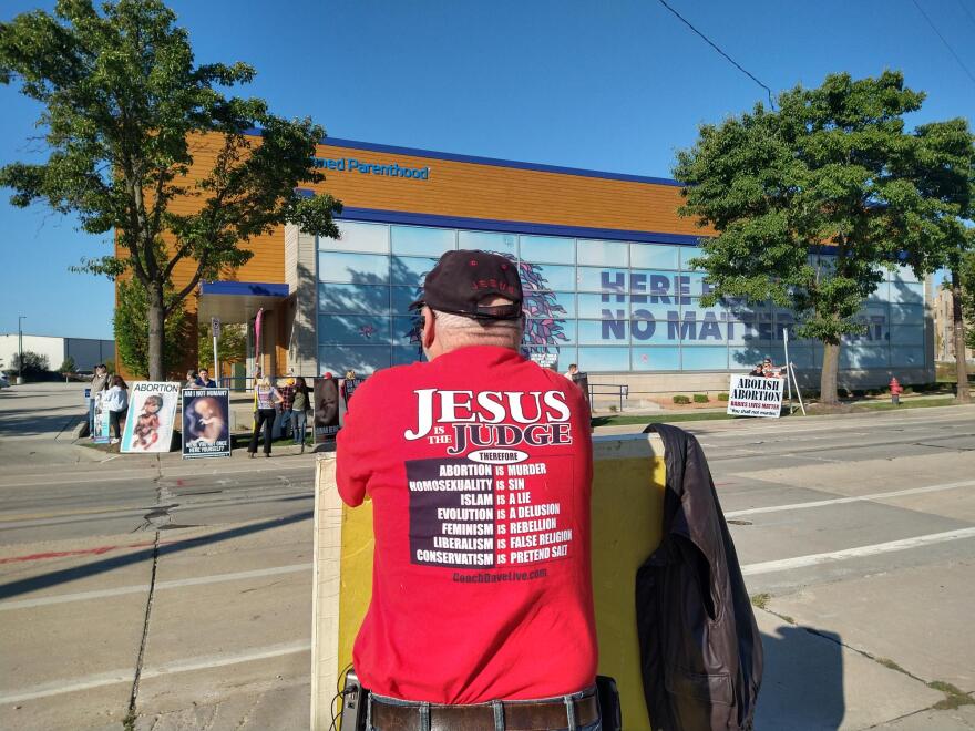 An anti-abortion protestor wearing a Jesus Is the Judge tee-shirt listened to speakers Monday, outside the Planned Parenthood clinic in Milwaukee.