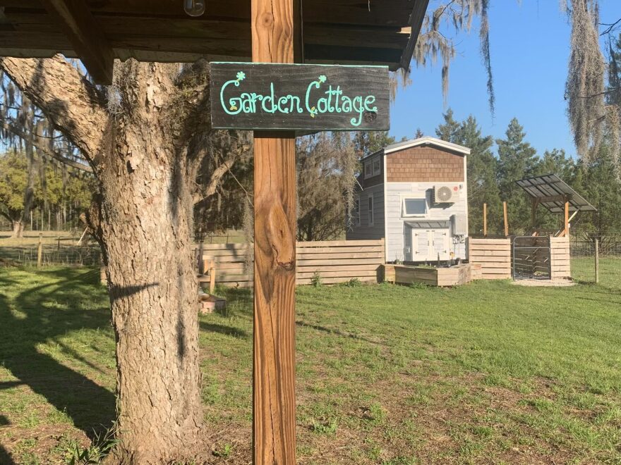 Garden Cottage sign on a post with a tiny home in the background