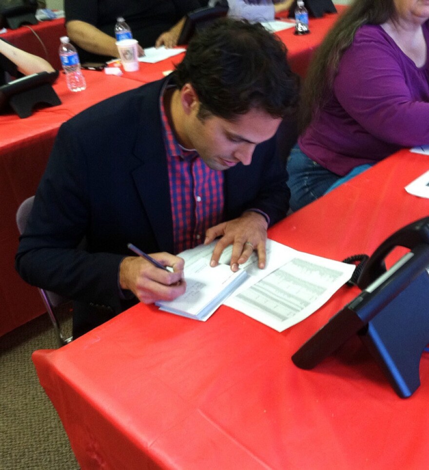 Craig Romney, the son of Republican presidential candidate Mitt Romney, signs postcards to voters at a campaign office in Aurora, Colo.