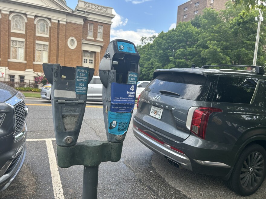 A Close-up of parking meters in downtown Athens. One of them is missing a head, the other has instructions on how to use a new parking app to pay parking fees.