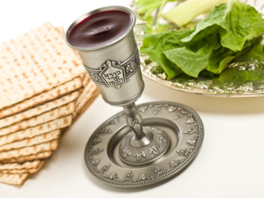 A kiddush cup, Seder plate and matzo for Passover. Words from the traditional Hebrew blessing of the wine are written on the cup.