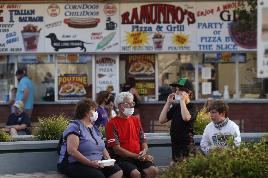 Visitors wear masks to help prevent the spread of the coronavirus, Wednesday, Aug. 5, 2020, at Old Orchard Beach, Maine. Tourists have returned to the popular seaside town in a state that ranks one of the lowest in the nation in positive cases of coronavirus.