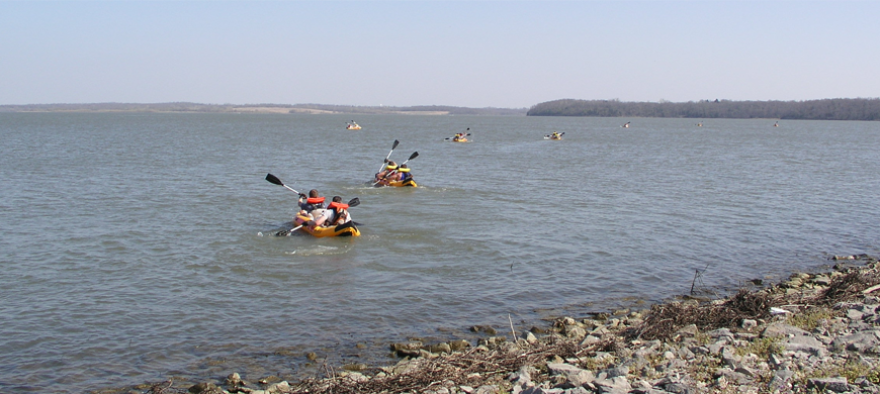 Pairs paddle along Hillsdale Lake outfitted in bright orange life vests.