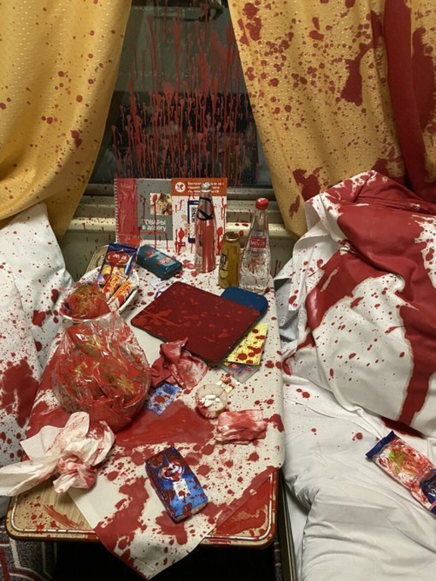 The aftermath of the attack on Muratov. Blood-red paint covers the train compartment and his belongings.