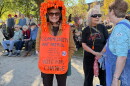 A woman wears a sign as other protesters gather behind her.