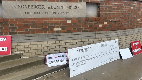 Protesters set signs down outside the Longaberger Alumni House at 2200 Olentangy River Rd., where the OSU Board of Trustees meet, after Thursday's meeting adjourned.